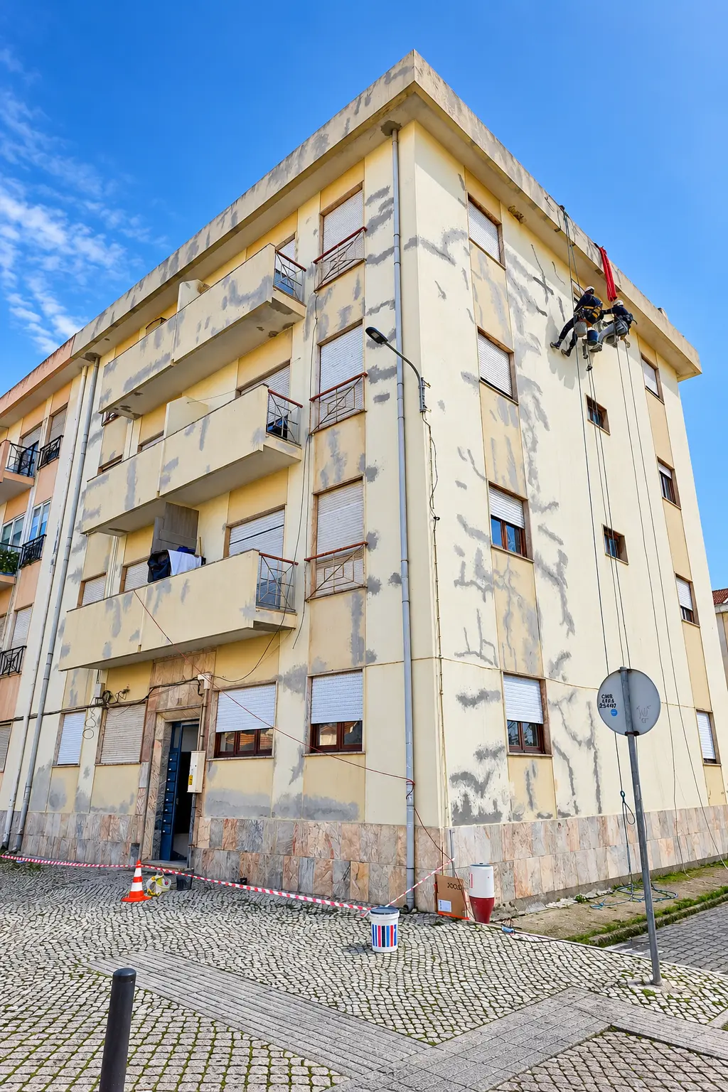 Fachada em preparação com reparações localizadas e técnicos suspensos em cordas