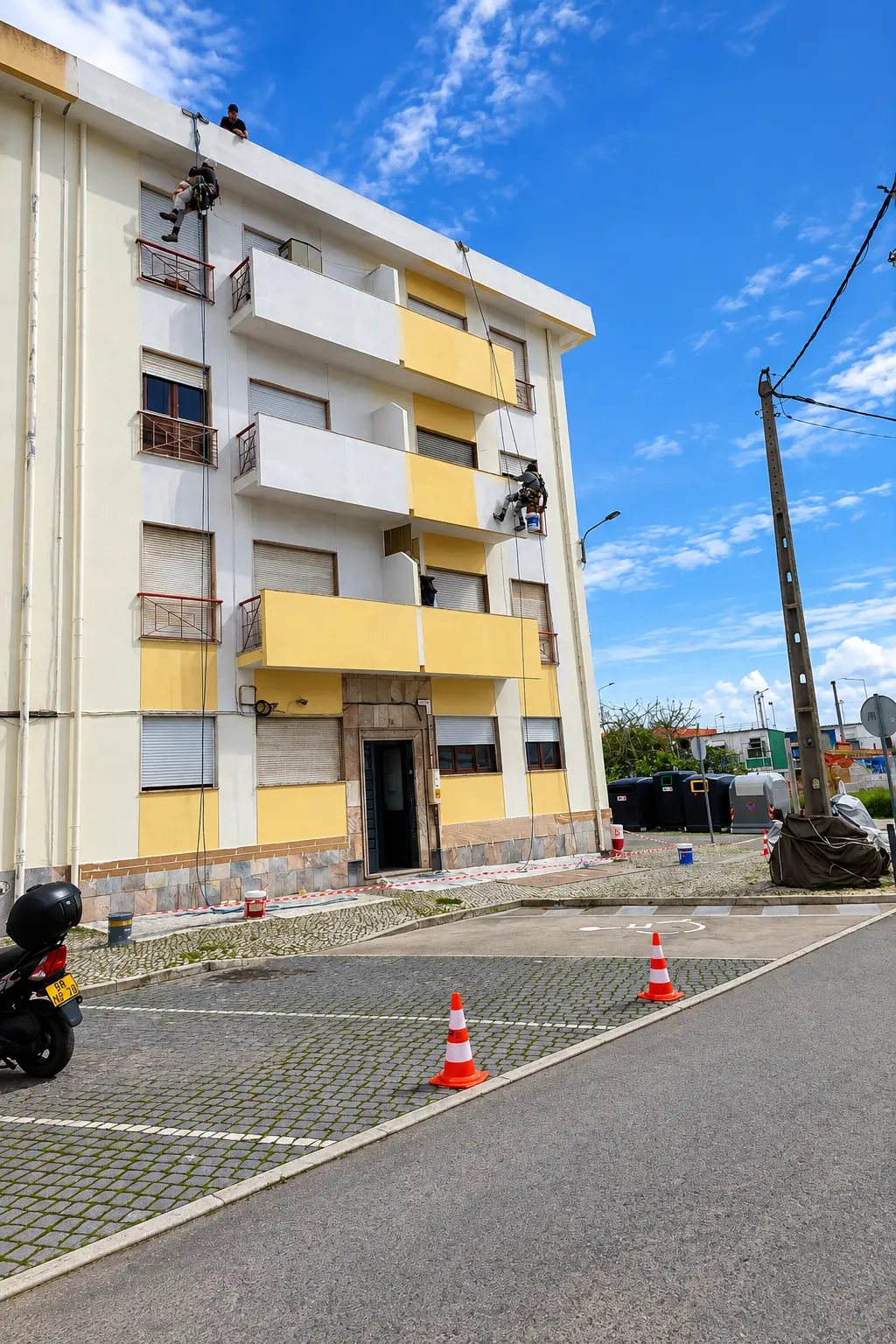 Técnicos em cordas a intervir numa fachada com varandas